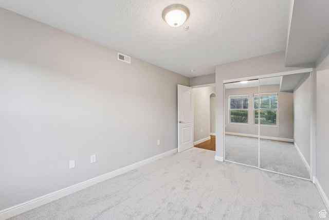 1729 Fox Bay Dr Unit J104, Heber City, UT 84032 - unfurnished bedroom featuring a textured ceiling, carpet flooring, a closet, and arched walkways