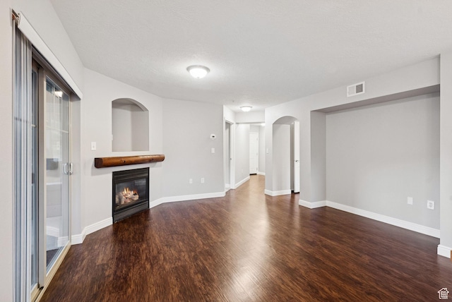 1729 Fox Bay Dr Unit J104, Heber City, UT 84032 - unfurnished living room featuring wood finished floors, a glass covered fireplace, arched walkways, and a textured ceiling