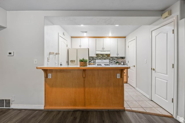 4072 S 300 E Unit 8, Salt Lake City, UT 84107 - kitchen with white refrigerator with ice dispenser, under cabinet range hood, range, a breakfast bar, and a peninsula