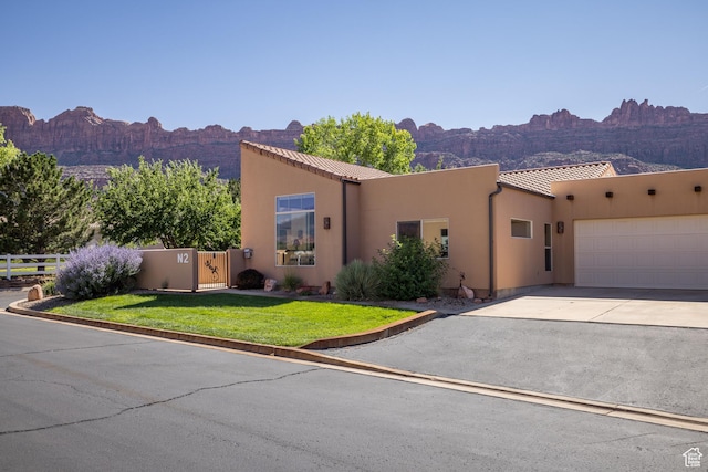 3686 S Spanish Valley Dr Unit N-2, Moab, UT 84532 - pueblo-style house featuring a mountain view, a tiled roof, driveway, stucco siding, and an attached garage