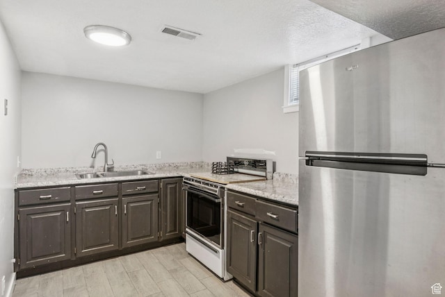 2353 E Logan Cir, Salt Lake City, UT 84108 - kitchen with freestanding refrigerator, white range with electric cooktop, light wood-type flooring, dark brown cabinets, and light stone countertops