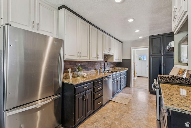 2353 E Logan Cir, Salt Lake City, UT 84108 - kitchen with appliances with stainless steel finishes, white cabinetry, tasteful backsplash, light stone countertops, and recessed lighting