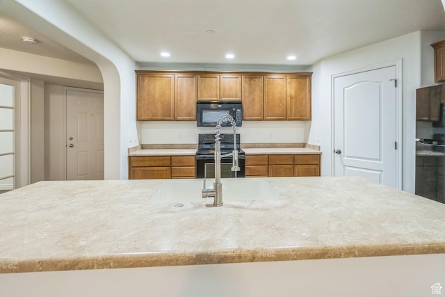 1195 W Dallin Dr Unit R-201, Pleasant Grove, UT 84062 - kitchen with black appliances, brown cabinets, recessed lighting, arched walkways, and light stone countertops