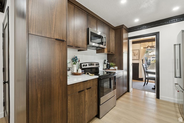 175 Grove Creek Dr N, Pleasant Grove, UT 84062 - kitchen with appliances with stainless steel finishes, light countertops, light wood-style flooring, dark brown cabinets, and recessed lighting