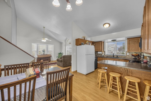 3820 Foxglen Dr, Roy, UT 84067 - kitchen with freestanding refrigerator, brown cabinetry, lofted ceiling, light wood-type flooring, and a peninsula