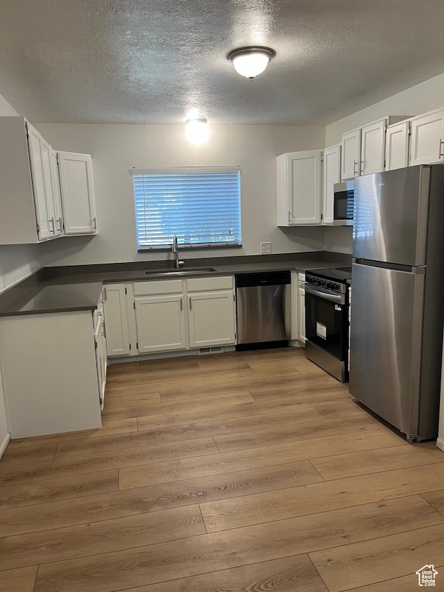 1455 N Amiron Way Unit A, Orem, UT 84057 - kitchen with stainless steel appliances, dark countertops, a textured ceiling, light wood-style flooring, and white cabinets