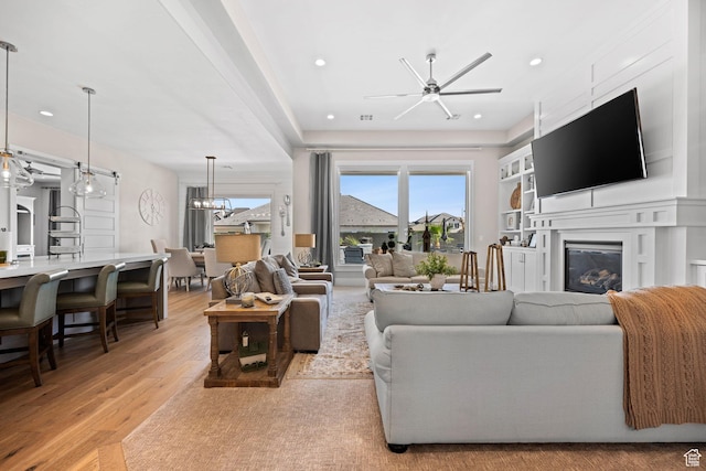 2918 E Willow Tree Ln, St George, UT 84790 - living room with a ceiling fan, light wood finished floors, a glass covered fireplace, recessed lighting, and a chandelier