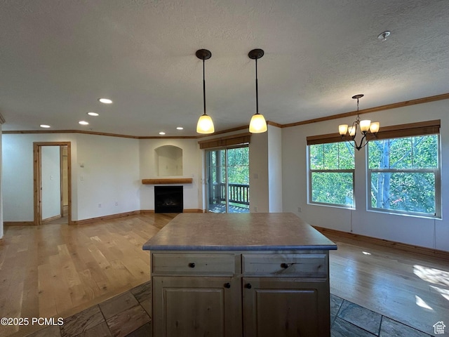 1729 Fox Bay Dr Unit J201, Heber City, UT 84032 - kitchen featuring crown molding, light wood-style floors, a fireplace, a chandelier, and a center island