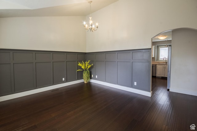 373 S 3240 W, Vernal, UT 84078 - spare room featuring a decorative wall, arched walkways, a chandelier, dark wood-style flooring, and a wainscoted wall