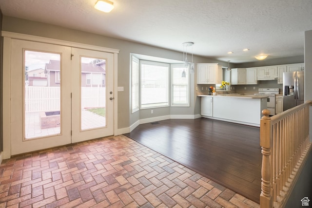 373 S 3240 W, Vernal, UT 84078 - kitchen with white range with electric stovetop, stainless steel fridge with ice dispenser, a peninsula, under cabinet range hood, and decorative light fixtures