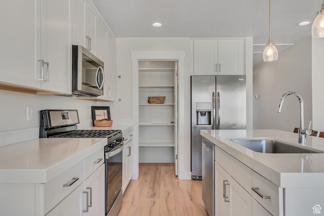 9728 N Aaron Ave Unit 115, Eagle Mountain, UT 84005 - kitchen with appliances with stainless steel finishes, decorative light fixtures, white cabinetry, light countertops, and light wood-style floors