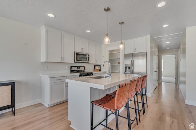 9728 N Aaron Ave Unit 115, Eagle Mountain, UT 84005 - kitchen featuring stainless steel microwave, gas range, light wood finished floors, a breakfast bar area, and light countertops