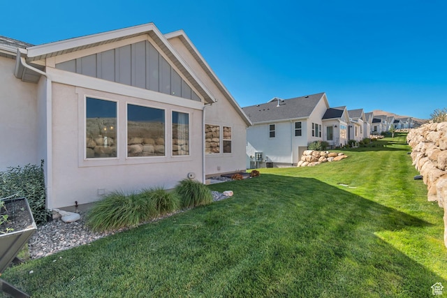 9728 N Aaron Ave Unit 115, Eagle Mountain, UT 84005 - rear view of property with board and batten siding, a yard, a residential view, and stucco siding