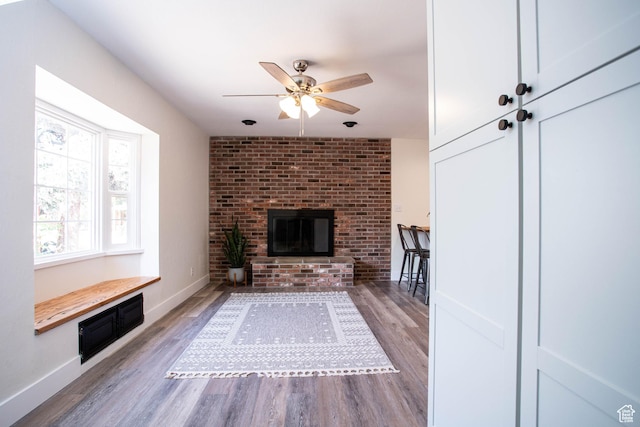 129 N 100 E, Ephraim, UT 84627 - unfurnished living room featuring wood finished floors, a ceiling fan, and a brick fireplace