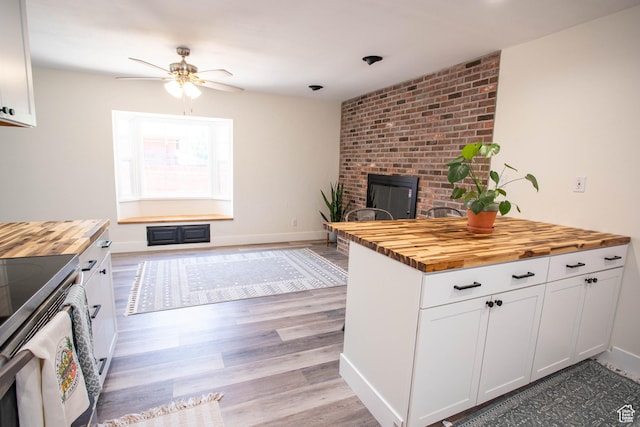 129 N 100 E, Ephraim, UT 84627 - kitchen with wooden counters, ceiling fan, stainless steel range with electric cooktop, a brick fireplace, and light wood-style floors