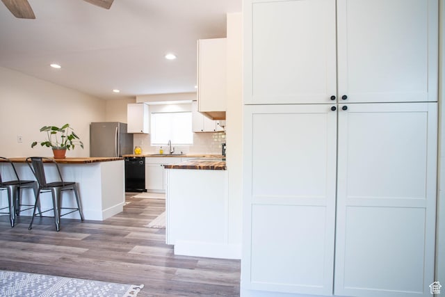 129 N 100 E, Ephraim, UT 84627 - kitchen with freestanding refrigerator, black dishwasher, white cabinets, light wood finished floors, and a breakfast bar area