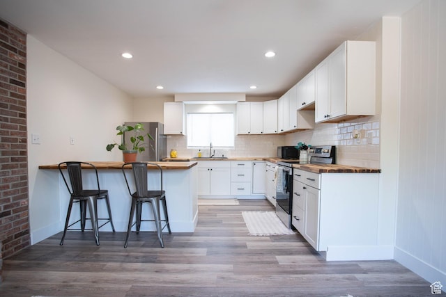 129 N 100 E, Ephraim, UT 84627 - kitchen with wooden counters, stainless steel appliances, a peninsula, a breakfast bar, and light wood-style floors