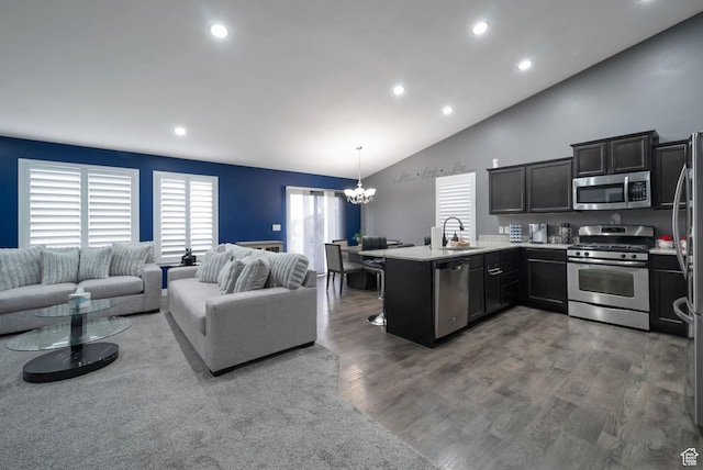 5198 W Courtly Ln, Herriman, UT 84096 - kitchen featuring appliances with stainless steel finishes, a peninsula, a chandelier, open floor plan, and vaulted ceiling