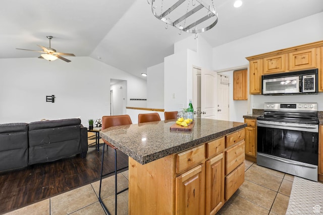 6228 S Waller Ln, West Jordan, UT 84081 - kitchen with stainless steel appliances, tile counters, a kitchen breakfast bar, light tile patterned flooring, and lofted ceiling