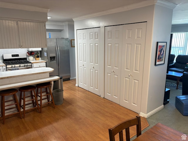 4208 S 4205 W, West Valley City, UT 84120 - kitchen with appliances with stainless steel finishes, crown molding, light countertops, light wood-type flooring, and a kitchen bar