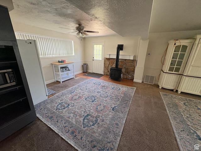 4208 S 4205 W, West Valley City, UT 84120 - living area with a wood stove, ceiling fan, a textured ceiling, carpet floors, and wainscoting