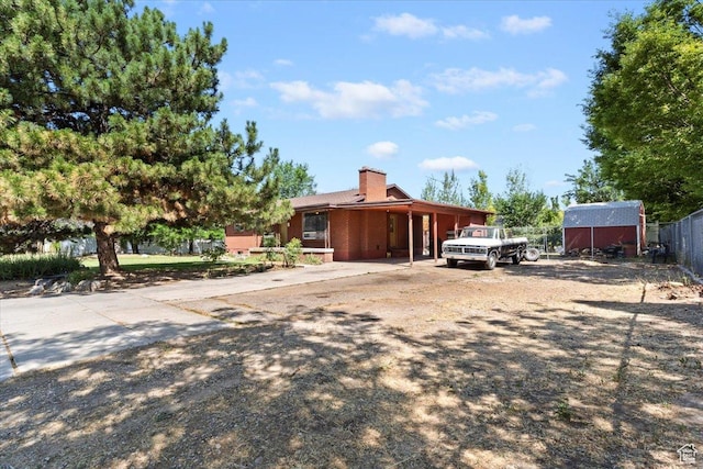 2262 W 2300 N, Clinton, UT 84015 - view of front of house with concrete driveway, an attached carport, a chimney, and an outdoor structure