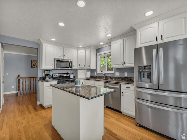 1834 N 200 E, Centerville, UT 84014 - kitchen with appliances with stainless steel finishes, white cabinetry, light wood-style floors, dark stone counters, and a kitchen island