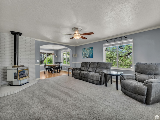 1834 N 200 E, Centerville, UT 84014 - living room featuring a wood stove, carpet floors, crown molding, ceiling fan, and arched walkways