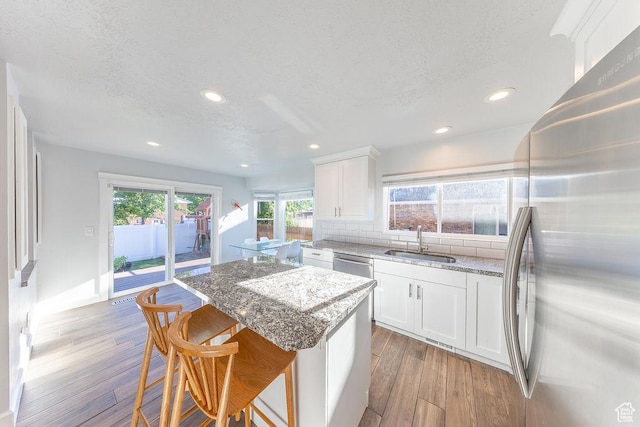 788 E 8230 S, Sandy, UT 84094 - kitchen with freestanding refrigerator, a textured ceiling, a kitchen island, light stone countertops, and wood finished floors