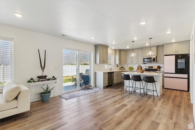 3380 W 3275 N, Plain City, UT 84404 - kitchen with appliances with stainless steel finishes, gray cabinets, a breakfast bar area, light countertops, and light wood-style flooring