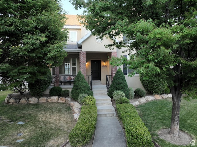 889 S Sego Lily Way, Mapleton, UT 84664 - obstructed view of property with stucco siding, a porch, a front yard, and brick siding