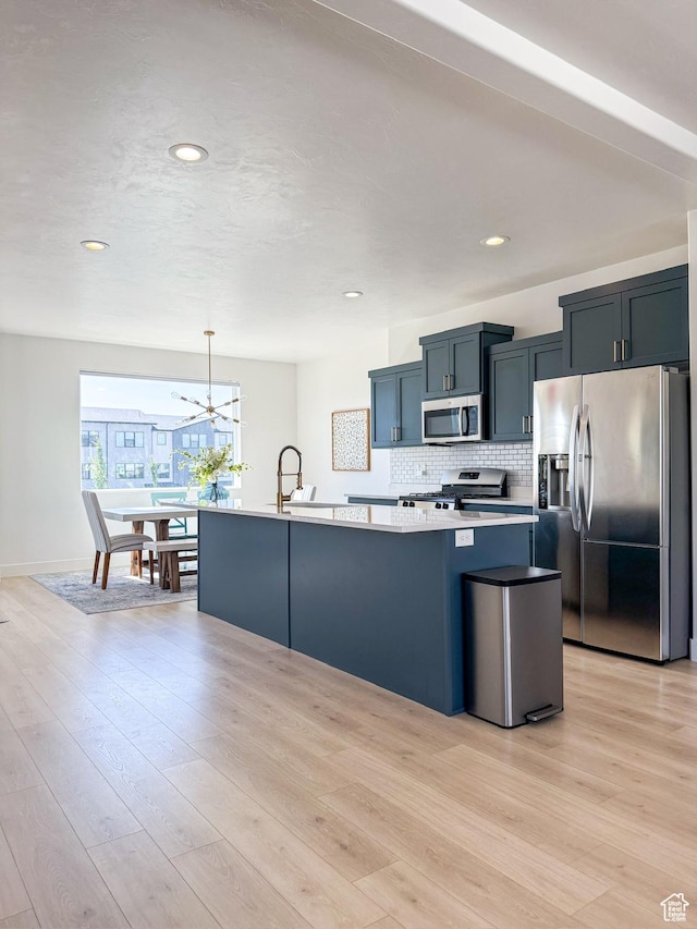 457 S Wood Stream Rd, American Fork, UT 84003 - kitchen featuring stainless steel appliances, light countertops, light wood finished floors, a center island with sink, and backsplash