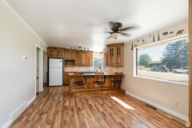 869 N 1600 E, Preston, ID 83263 - kitchen featuring freestanding refrigerator, brown cabinets, a peninsula, decorative backsplash, and a ceiling fan