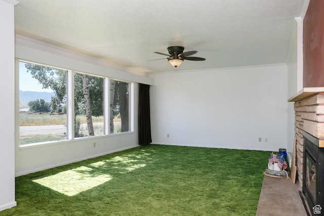 869 N 1600 E, Preston, ID 83263 - unfurnished living room featuring a stone fireplace, carpet floors, ceiling fan, crown molding, and a mountain view