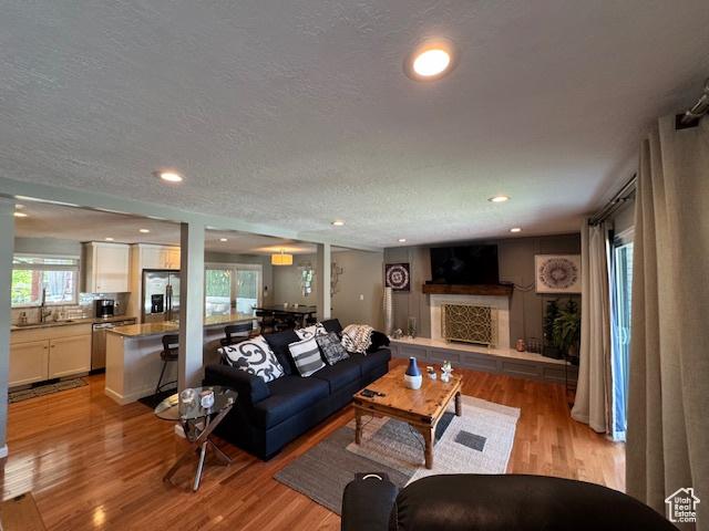 4650 S Chapel Dr E, Salt Lake City, UT 84117 - living room with light wood-type flooring, a textured ceiling, a fireplace with raised hearth, and recessed lighting