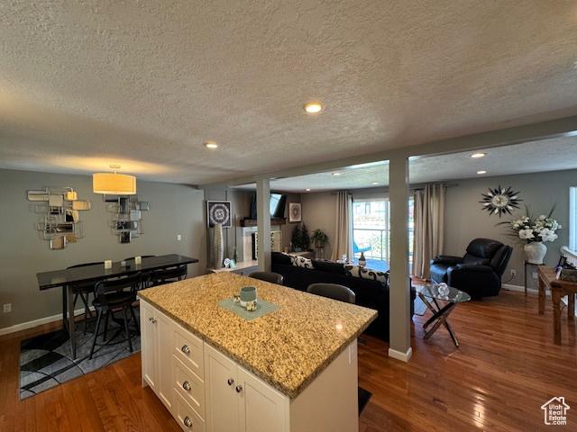4650 S Chapel Dr E, Salt Lake City, UT 84117 - kitchen with a textured ceiling, dark wood-style floors, a kitchen island, open floor plan, and white cabinets