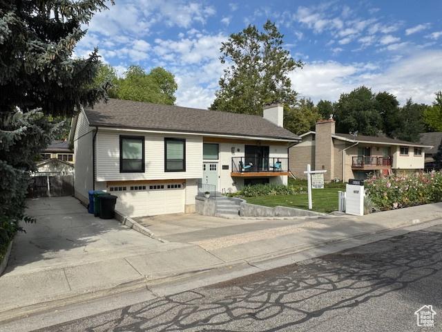 4650 S Chapel Dr E, Salt Lake City, UT 84117 - raised ranch featuring concrete driveway, an attached garage, and a chimney
