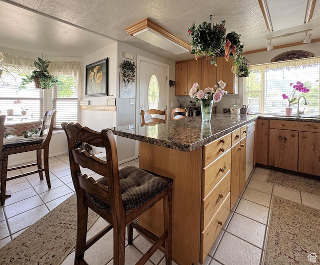 804 Fleetwood Dr, Tooele, UT 84074 - kitchen with dishwasher, a peninsula, dark stone countertops, light tile patterned floors, and brown cabinets