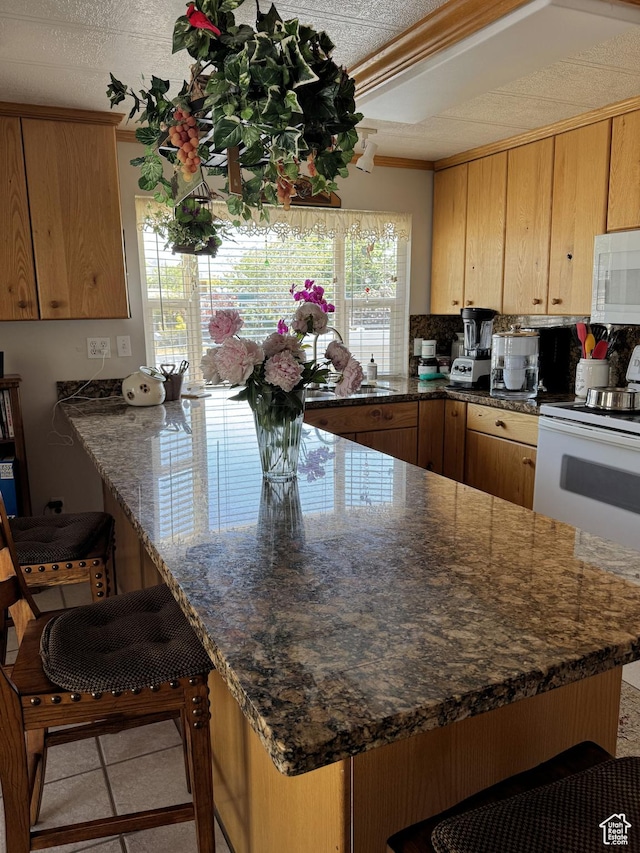 804 Fleetwood Dr, Tooele, UT 84074 - kitchen featuring white appliances, a peninsula, a breakfast bar, and dark stone counters