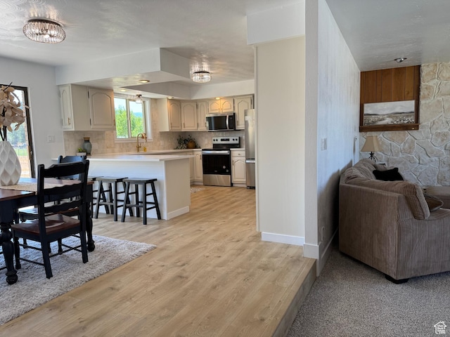 262 N 400 E, Fairview, UT 84629 - kitchen with appliances with stainless steel finishes, a peninsula, open floor plan, a chandelier, and a breakfast bar area