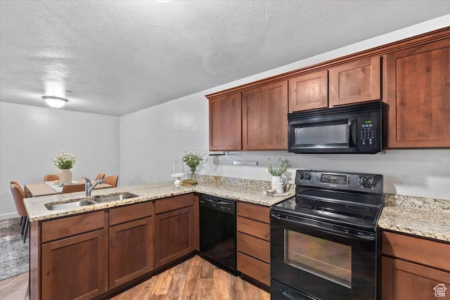 491 S Freedom Blvd Unit 104204, Provo, UT 84601 - kitchen featuring black appliances, a peninsula, light wood finished floors, light stone countertops, and a textured ceiling