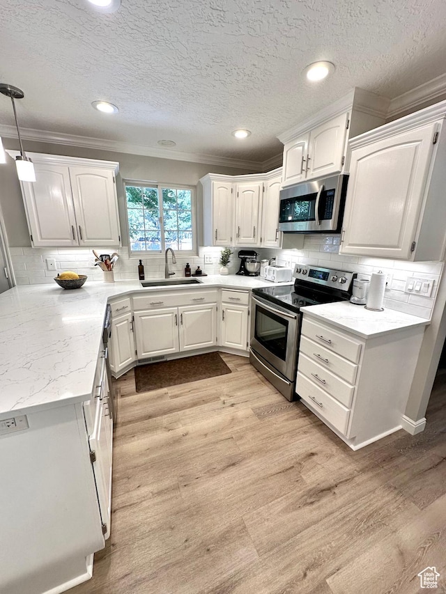 2442 N 2275 E, Layton, UT 84040 - kitchen with stainless steel appliances, crown molding, white cabinetry, tasteful backsplash, and light wood-style floors