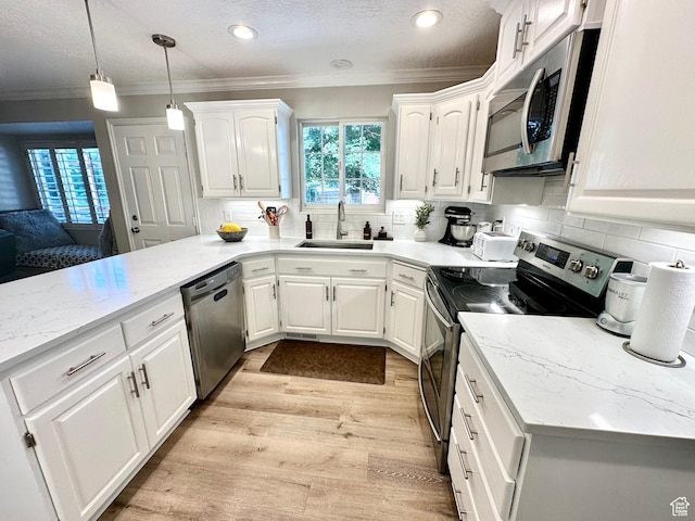 2442 N 2275 E, Layton, UT 84040 - kitchen with stainless steel appliances, crown molding, a peninsula, white cabinets, and light wood finished floors