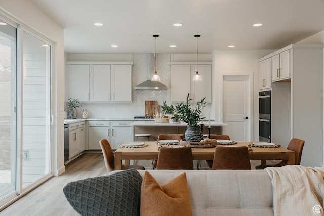 5976 N Canyon Rim Rd E Unit 615, Lehi, UT 84043 - kitchen featuring wall chimney range hood, light wood-style floors, backsplash, light countertops, and recessed lighting