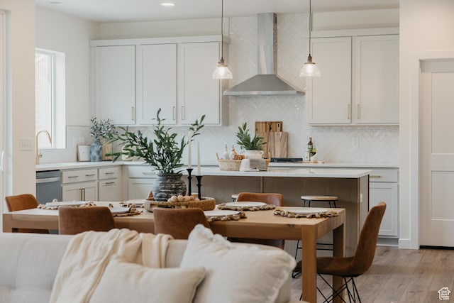 5976 N Canyon Rim Rd E Unit 615, Lehi, UT 84043 - kitchen with wall chimney exhaust hood, stainless steel dishwasher, light countertops, light wood-style flooring, and decorative backsplash