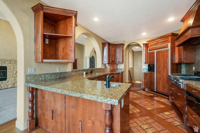 238 N Vista Ct, Saratoga Springs, UT 84045 - kitchen with paneled built in refrigerator, premium range hood, stainless steel gas cooktop, arched walkways, and light stone countertops