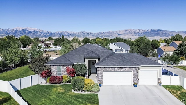406 Zachary Way, Grantsville, UT 84029 - view of front of house with an attached garage, stone siding, driveway, a fenced backyard, and a mountain view