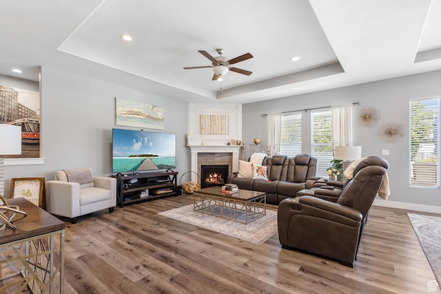 406 Zachary Way, Grantsville, UT 84029 - living room with a tray ceiling, wood finished floors, a lit fireplace, ceiling fan, and recessed lighting