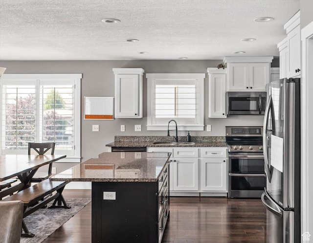 4449 W 5325 S, Hooper, UT 84315 - kitchen featuring appliances with stainless steel finishes, dark wood-style floors, dark stone counters, white cabinets, and a center island