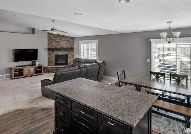 4449 W 5325 S, Hooper, UT 84315 - kitchen featuring ceiling fan, dark cabinetry, dark wood-type flooring, a stone fireplace, and a textured ceiling